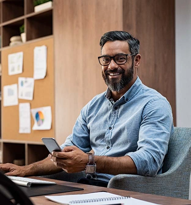 Male At Desk Smiling While Sending Remittance Advice To Suppliers From Business Central