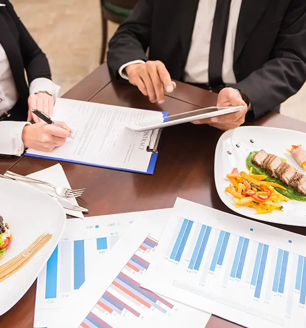 Business professionals discussing documents and enjoying a meal together for the daily allowances page thumbnail